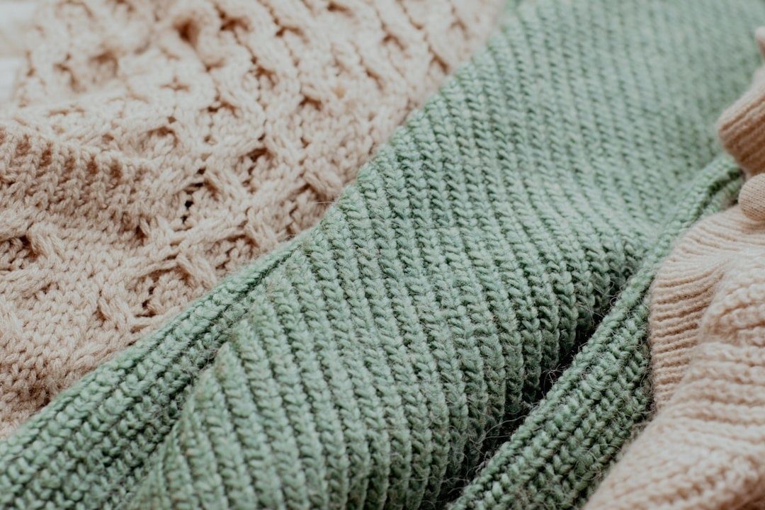 Nærbilde av myke, strikkede tekstiler i grønt og naturfarget ull