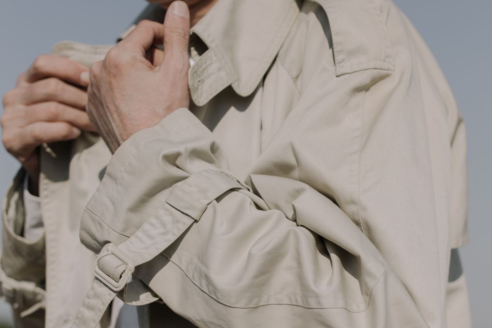 Nærbilde av person i klassisk beige trenchcoat med belte